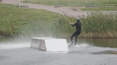 Kafkasyalı yetişkin sörfçü erkek sörfçünün kablo parkında halatla kayarak kayışının tam karesi.