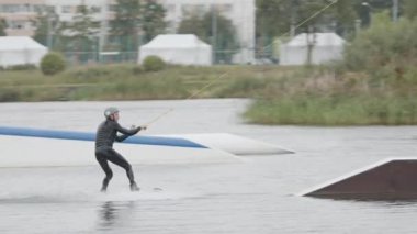 Kendine güvenen erkek wakeboard binicisinin kablo parkında süratle kayarken görüntüsü.