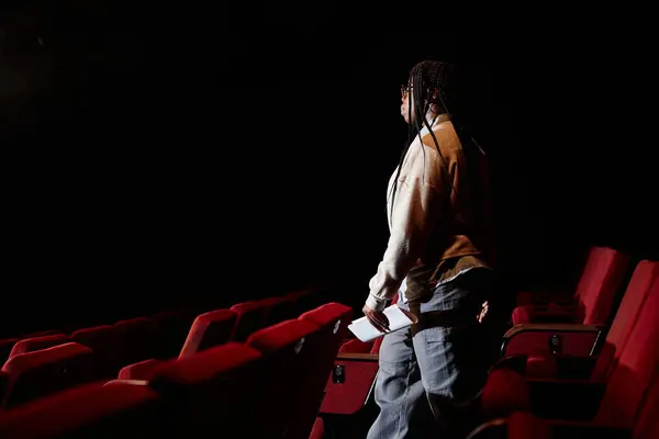 Side view portrait of African American woman walking down to stage in empty theater copy space
