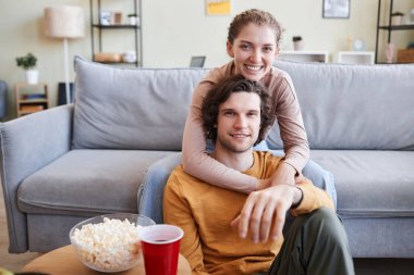 Tasasız genç bir çiftin evde televizyon izlediği ve kameraya bakıp uzayı kopyaladığı portre.