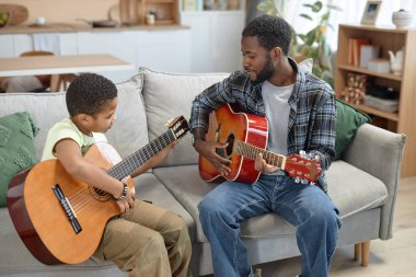 Evde akustik gitar çalan Afrikalı Amerikalı genç bir çocuğun portresi. Müzik derslerinde yer kopyalama.