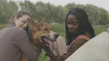 Parkta köpek yavrusuyla oynayan iki neşeli kadının yavaşlığı.