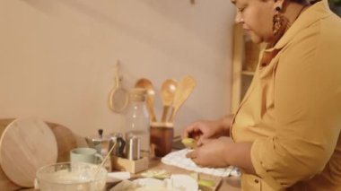 Olgun siyahi bir kadının evde elmalı turta yaparken yuvarlak metal pasta kalıbının içine elma koyduğu orta boy bir fotoğraf.