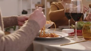 Tanımlanamayan üç yetişkinin, rahat bir dairede, yuvarlak masada yemek yerken çekilmiş kavisli görüntüleri.