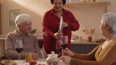 Çok ırklı eski arkadaşlarına fotoğraf albümü gösteren orta yaşlı siyahi bir kadın. Parlak bir dairede küçük bir akşam yemeği partisi veriyor.