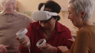 Evde VR oynarken eğlenen üç çok ırklı yaşlı arkadaşın orta boy fotoğrafı.