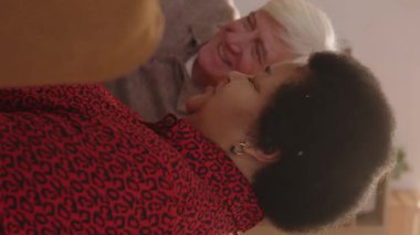 Gençlik anılarını yad ederken gülen bir grup çok ırklı yaşlının dikey görüntüsü. Parlak, rahat bir dairede toplanıyorlar.