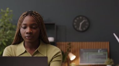 Modern ve yeşil ofiste çalışan ve arka planda iletişim kuran birkaç meslektaşı olan genç ve güzel Afro-Amerikan bayanın sandığı.