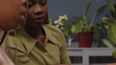 Sürdürülebilir yeşil çalışma alanı projesinde çalışırken dizüstü bilgisayara bakan ve konuşan iki genç Afrikalı Amerikalı kadın ofis çalışanının sandığı.