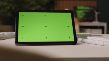 Modern ofisteki masada yeşil şablon ekranlı dijital tablete yakın çekim yapan kimse yok