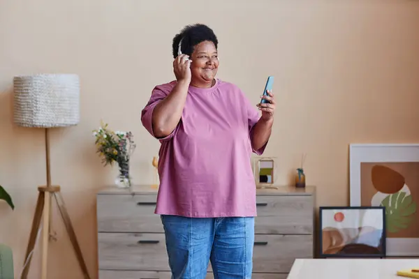 Femme Afro Américaine Gaie Senior Avec Smartphone Écoutant Musique Préférée Image En Vente