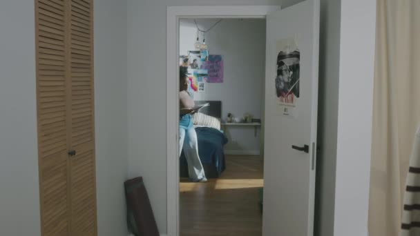 全景拍摄的年轻黑人女生身穿宽松的便服 手拿着纸片走在公寓边 一边为高考准备学习材料 — 图库视频影像