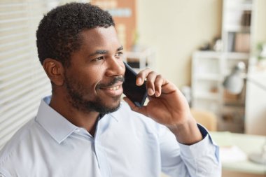 Ofisten arayan ve gülümseyen siyahi iş adamının yakın plan portresi.