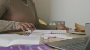 Afrika kökenli Amerikalı genç bir kadının çalışma materyalleri, ders kitapları ve dizüstü bilgisayarla masaya oturup üniversitede ev ödevi yapması, beyaz kadın oda arkadaşıyla yaşaması.