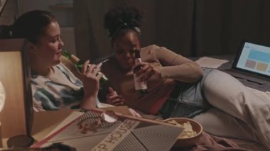 Etnik çeşitlilikte iki genç bayan en iyi arkadaş. Gece yatıya kalırken bira içip yatakta sohbet ediyorlar.