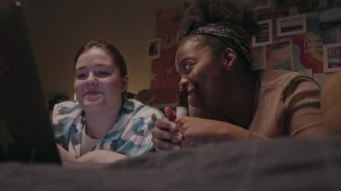 Pijama partisi sırasında laptopta film izlerken elma şarabı içip sohbet eden iki genç kız arkadaşın sandığı.