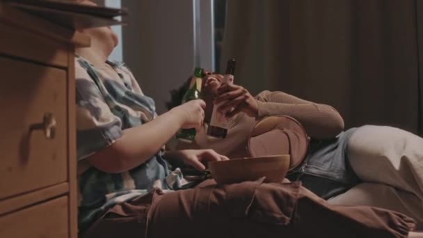 Две Многоэтнические Веселые Девушки Лежат Кровати Бутылками Сидра Сплетничают Время — стоковое видео