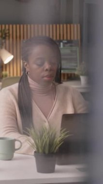 Modern ve yeşil ofiste çalışan ve dizüstü bilgisayarın önünde oturan genç siyahi kadın çalışanın dik beli.