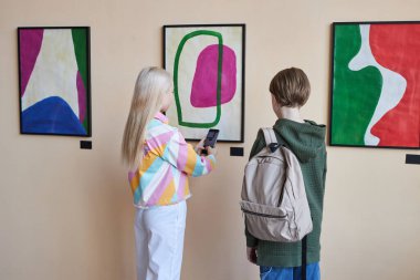 Sanat galerisinde ya da müzede sergilenen soyut sanat eserlerine bakan iki gencin minimum arka planı, boşluğu kopyalamak.