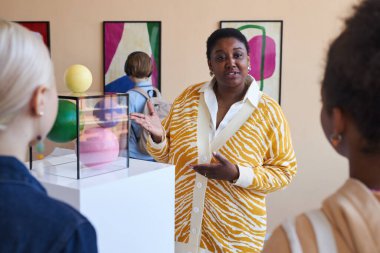 Modern sanat galerisinde siyahi genç kadınları dinleyen çeşitli gençlerden oluşan bir grup.