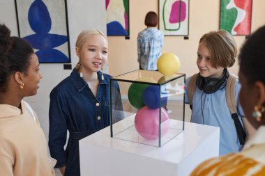 Modern sanat galerisindeki soyut heykellere bakan çeşitli gülümseyen genç çocuklar.