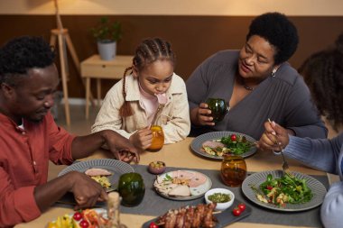 Büyük Afrikalı Amerikalı bir ailenin birlikte yemek yemesi ve evde oturması.