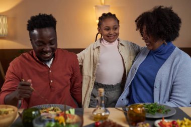 Sevimli Afro-Amerikan kız portresi yemek masasında ailesi mutlu bir şekilde gülümsüyor.