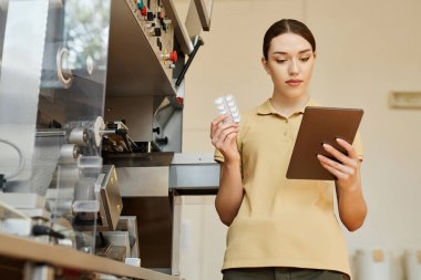 İlaç fabrikasındaki prodüksiyonları denetlerken dijital tablet kullanan genç bir kadının belden yukarı portresi.