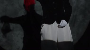 Sahne ışıkları altında seyirciye sihirli numaralar gösterirken renkli parlayan giysiler kullanan yaratıcı kadın pandomimcinin dikey eğim çekimi.