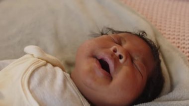 Afro-Amerikan yeni doğan bebeğinin yaklaşması gözleri kapalı ve esniyor, öğle uykusundan uyanıyor.