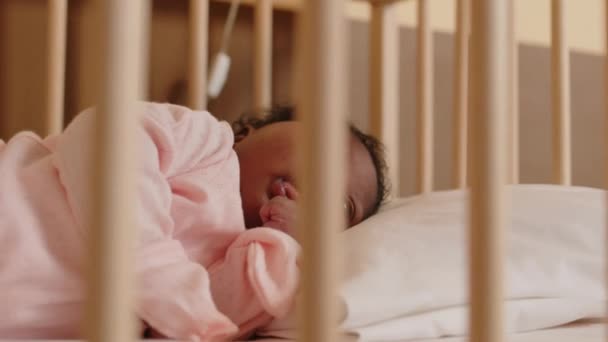 可爱的小非洲裔美国女婴穿着浅粉色的连衣裙躺在舒适的婴儿床里 — 图库视频影像