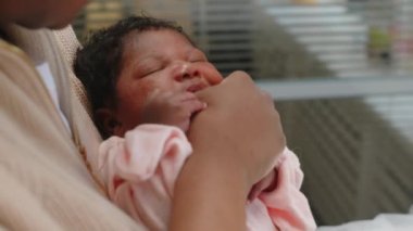 Tatlı uykucu Afrikalı Amerikalı bebek annesinin kollarında ağzı açık yatıyor.