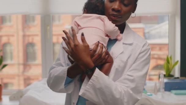Portret Młodej Czarnej Pediatry Trzymającej Ramionach Małą Afroamerykańską Dziewczynkę Uśmiechającą — Wideo stockowe