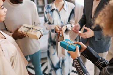 Birkaç kültürler arası genç insanın elleri kameranın önünde dikilirken hediye kutularını birbirlerine uzatıyor.