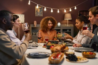 Kültürler arası genç kadın ve erkeklerden oluşan bir grup festival masasında oturmuş, iletişim kuruyor ve ev yapımı yiyecek ve içecekler hazırlıyorlar.