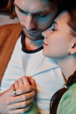 Genç çiftin birbirine sarılıp evde vakit geçirmesinin dikey görüntüsü.