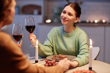 Kocasıyla şarap içen ve evde romantik yemek yiyen genç bir kadının portresi.