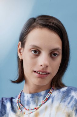 Engelli bir kızın dikey güzellik portresi moda kıyafetler giyip kameraya bakıyor.