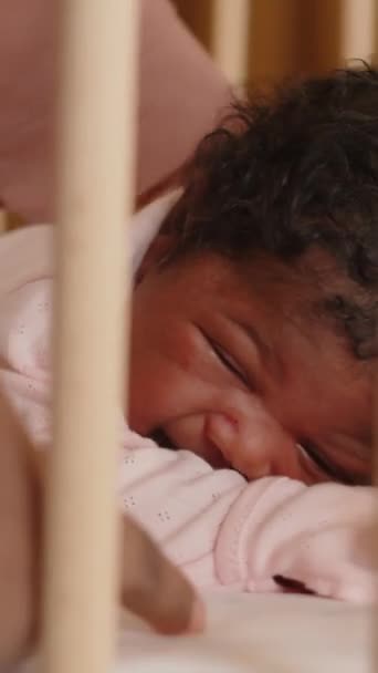 非洲裔美国女婴在床上躺在婴儿床里哭泣 而母亲则试图通过抚摸她的背来安慰她 — 图库视频影像