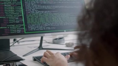 Kıvırcık saçlı erkek yazılım mühendisi gündüzleri modern bilişim ofisinde çalışırken bilgisayarda html kod yazıyor.
