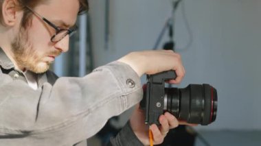 Beyaz tenli genç fotoğrafçının beline güneş ışığı altındaki fotoğraf stüdyosunda profesyonel dijital kamera ile fotoğraf çektirmesi.
