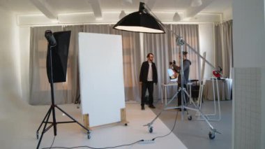 Fotoğrafçı ve asistanlardan oluşan profesyonel yapım ekibinin kamera önünde iç çamaşırlı beyaz bir erkek vücut geliştiriciyi vurması, ışığı ayarlaması ve fotoğraf çekmesi...