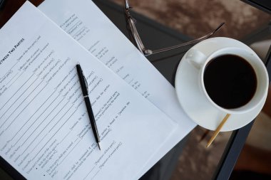 Ofisteki cam masanın üzerinde sözleşmelerin ve kahve fincanının üst görünümü, boşluğu kopyala