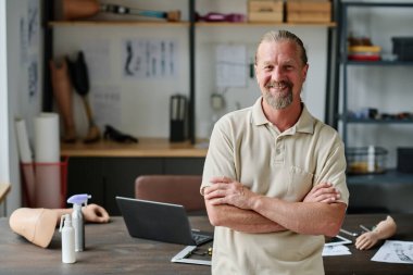 Protez atölyesinde kameraya bakan gülümseyen son sınıf öğrencisinin belden yukarı portresi.