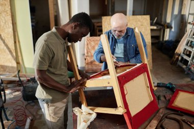 Portrait of two people repairing old furniture while working in carpentry workshop together, copy space clipart