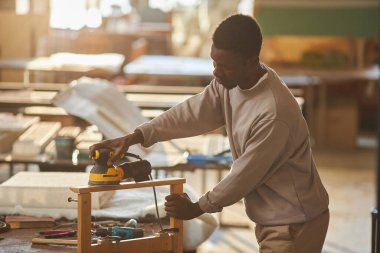 Güneş ışığında ahşap mobilyalar yapan genç siyahi adamın yan görünüm portresi, boşluğu kopyala
