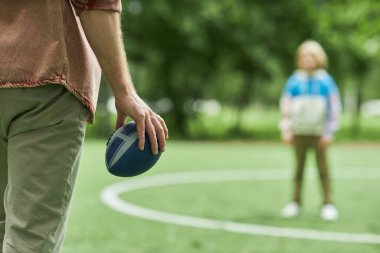 Baba ve oğlunun parkta Amerikan futbolu oynamaları, el ele tutuşmaları, fotokopi çekmeleri.