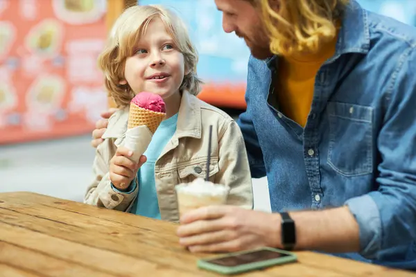 Portrait of father and son eating ice cream and enjoying bonding time together
