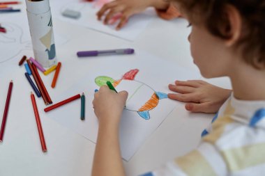 Anaokulundaki sanat ve el sanatları sınıfındaki deniz kaplumbağası resimlerini boyayan oğlanın resmini kapat.