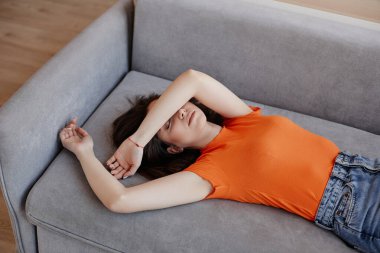 Evdeki kanepede uzanmış depresyonla boğuşan genç bir kadın.